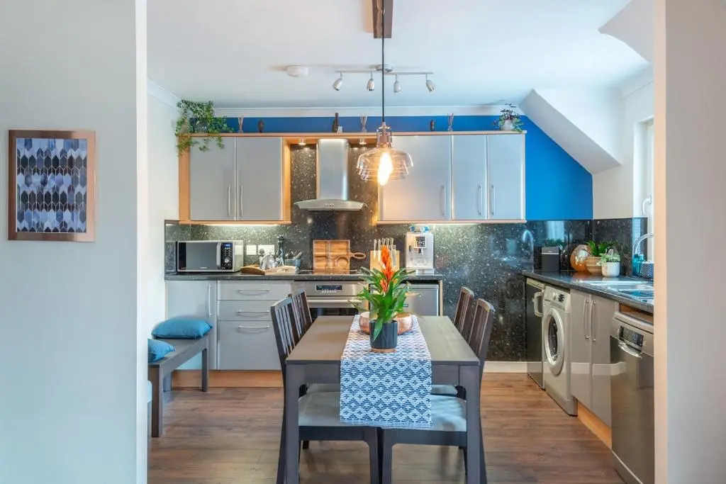 a kitchen with a table and chairs and blue cabinets at An I\u00f9bhrach in Inverness