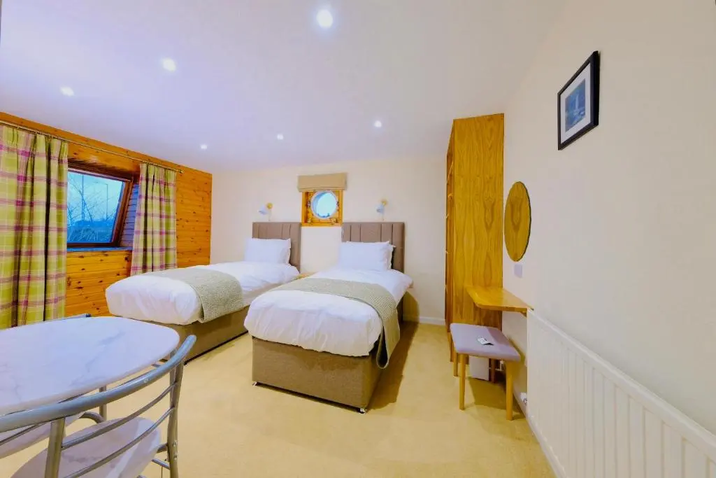a hotel room with two beds and a window at Suilven Cottage in Tain