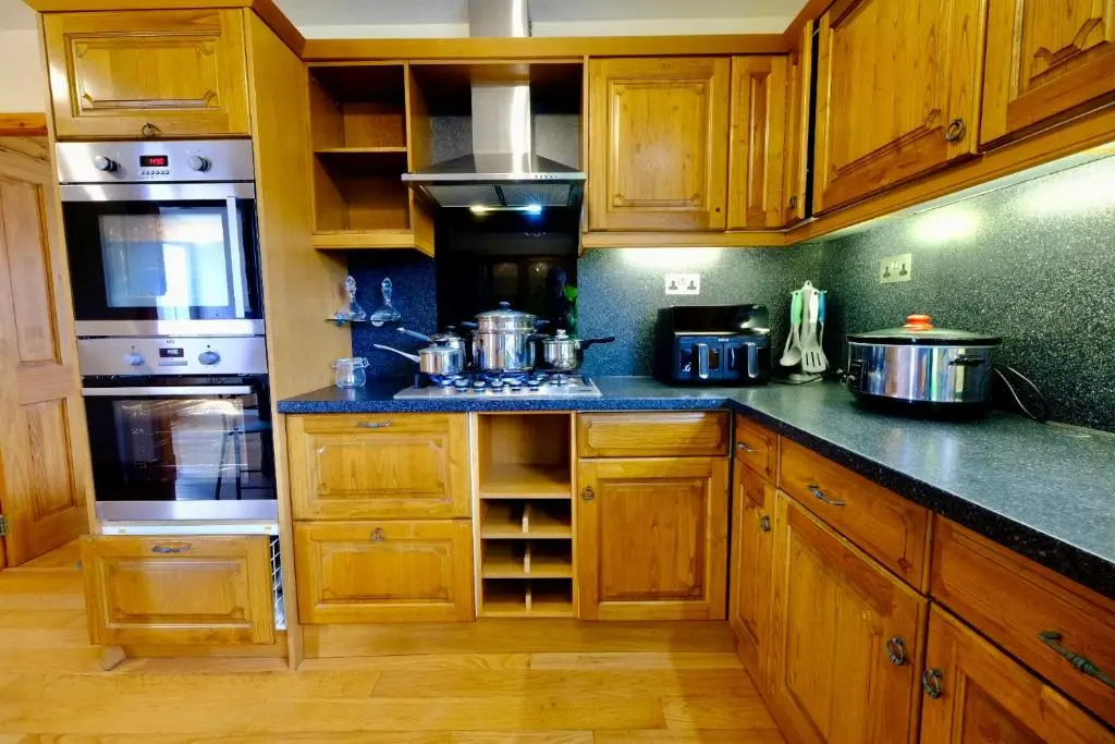 a kitchen with wooden cabinets and stainless steel appliances at Suilven Cottage in Tain