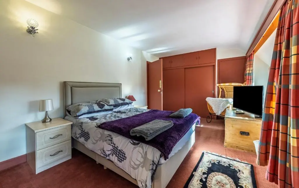 a bedroom with a bed and a desk and a television at Finest Retreats - White House Retreat in Cornhill