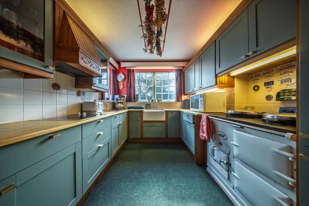 a large kitchen with blue cabinets and a window at Finest Retreats - White House Retreat in Cornhill