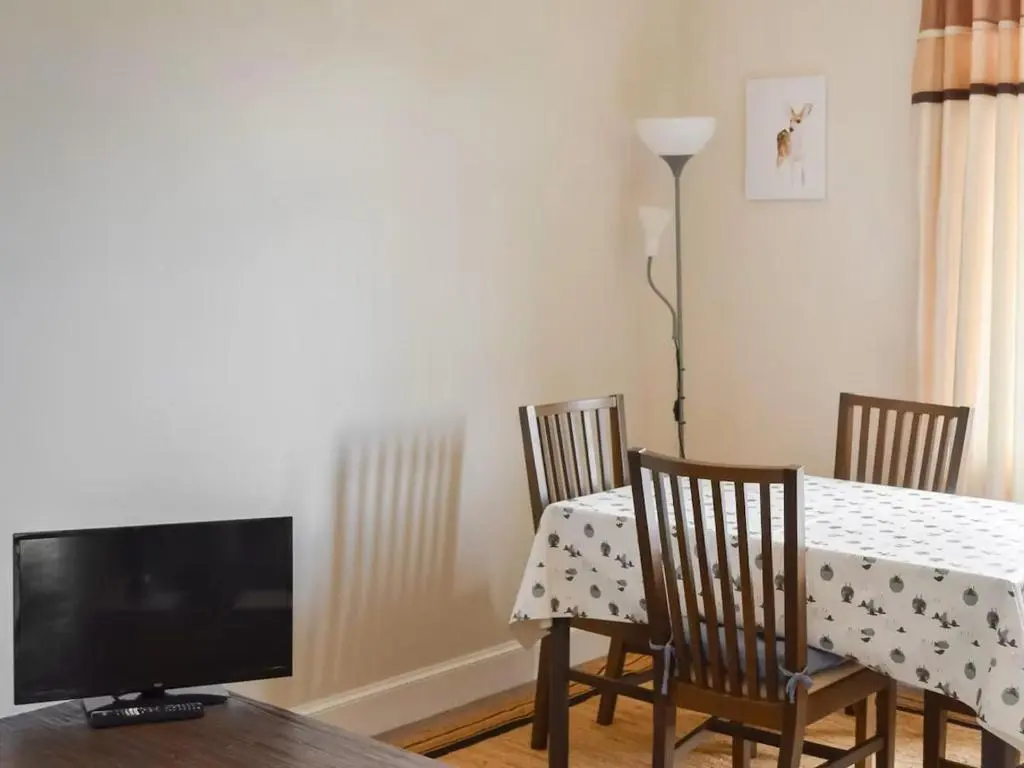 a dining room with a table with chairs and a television at Inverness Haven - with Parking and Garden in Dalneigh