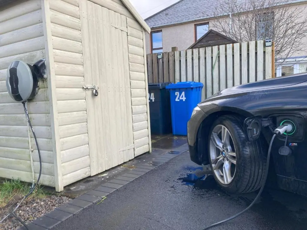 a car is parked next to a fence with a hose at Inverness Haven - with Parking and Garden in Dalneigh