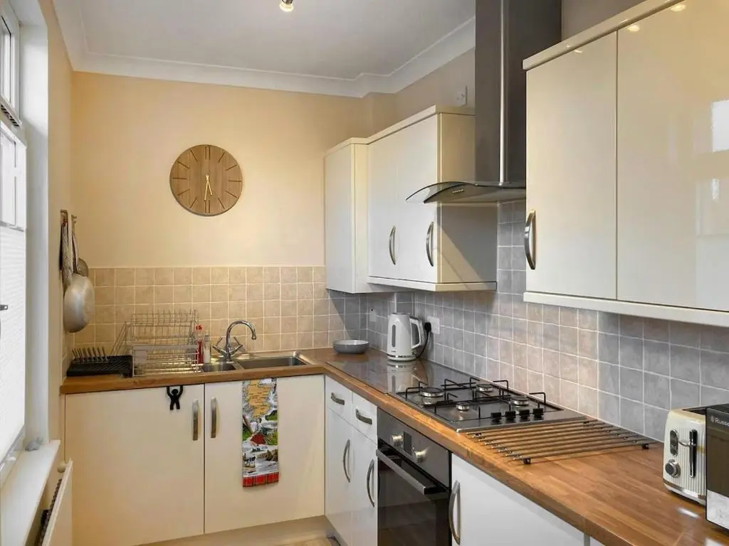 a kitchen with white cabinets and a clock on the wall at Inverness Haven - with Parking and Garden in Dalneigh