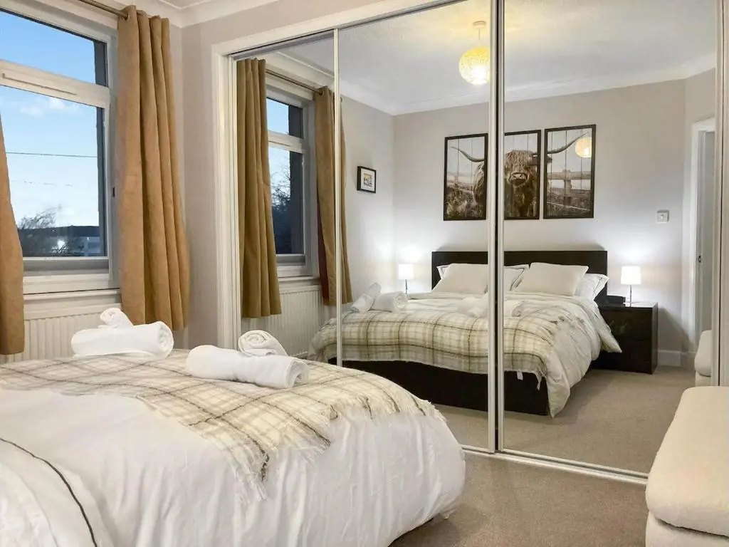 a bedroom with two beds and a large mirror at Inverness Haven - with Parking and Garden in Dalneigh