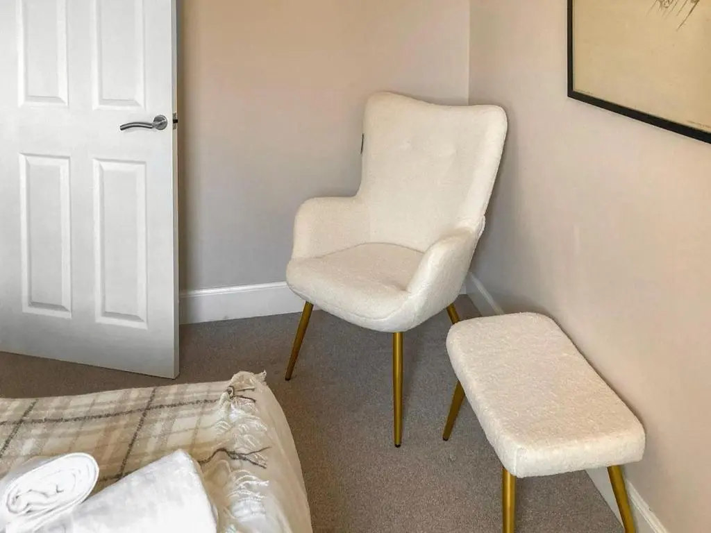 a white chair and a stool in a room at Inverness Haven - with Parking and Garden in Dalneigh