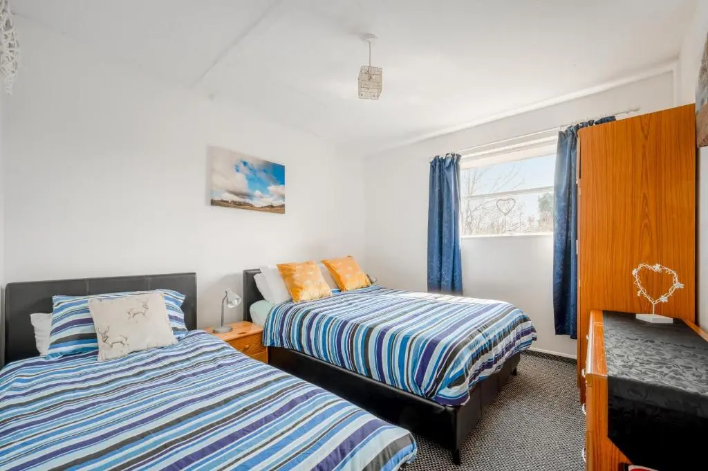 a bedroom with two beds and a window at 2 Bed Chalet - Sleeps 3 - River and mountain views in Strathpeffer