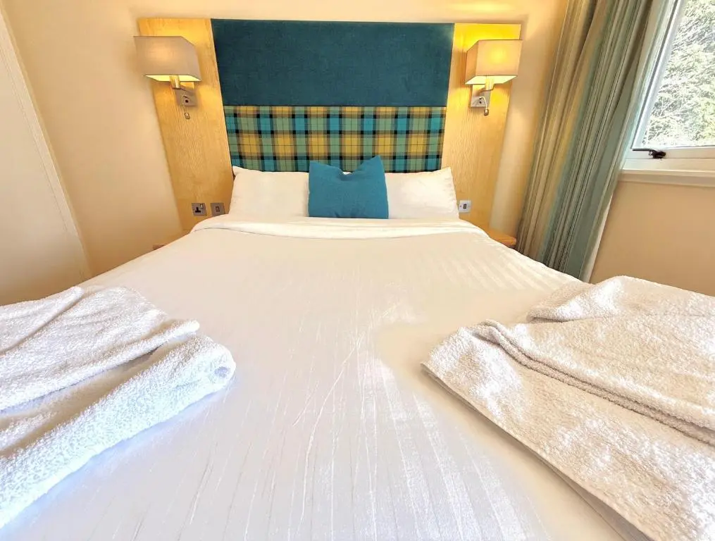 a bedroom with a large white bed with towels on it at Seabank House Hotel in Nairn