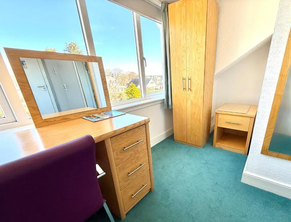 a room with a desk with a mirror and a window at Seabank House Hotel in Nairn