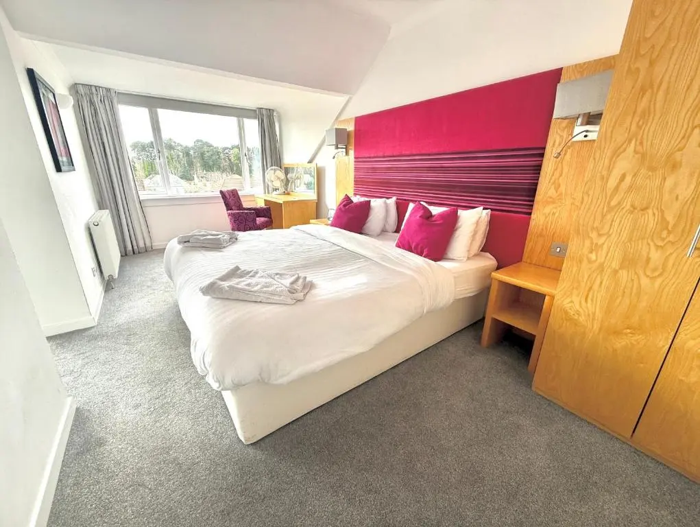 a bedroom with a large bed with pink walls at Seabank House Hotel in Nairn