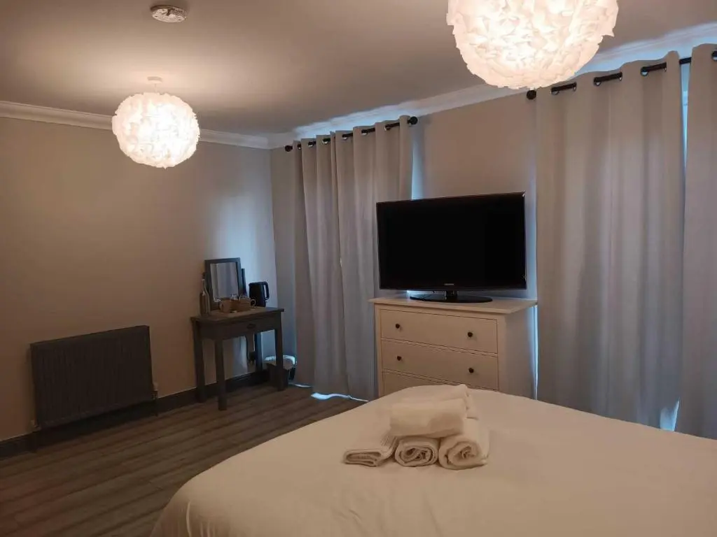 a bedroom with a bed and a flat screen tv at Woodgrove Holiday Homes in Inshes