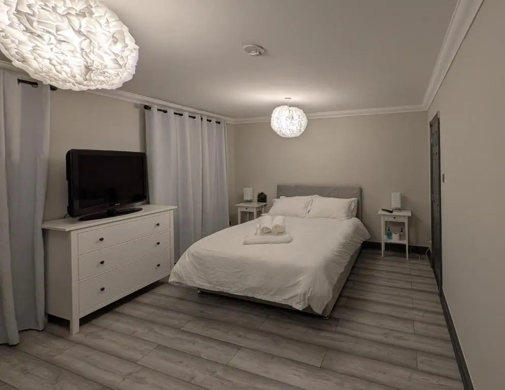 a bedroom with a bed and a tv on a dresser at Woodgrove Holiday Homes in Inshes