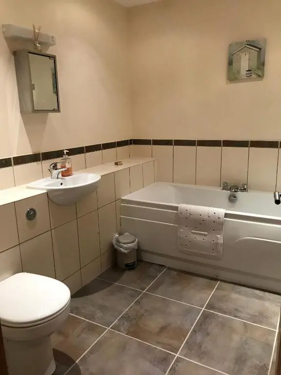 a bathroom with a toilet and a tub and a sink at The Town House in Dornoch
