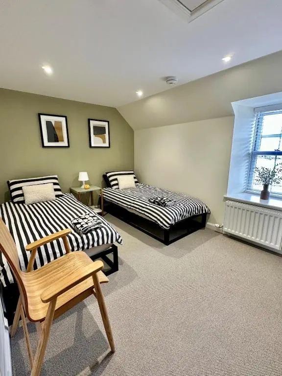 two beds in a room with a chair and a window at Luxury Coastal Cottage in Portsoy
