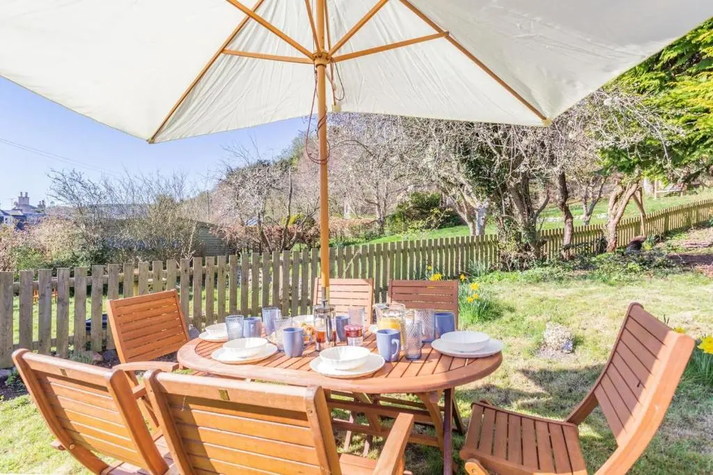 a wooden table with an umbrella in a yard at 3 Bed in Avoch oc-c31805 in Avoch