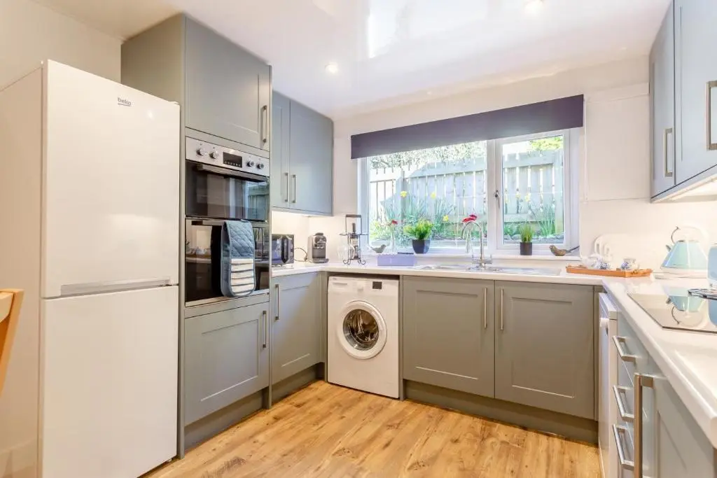 a kitchen with white cabinets and a washer and dryer at 3 Bed in Avoch oc-c31805 in Avoch