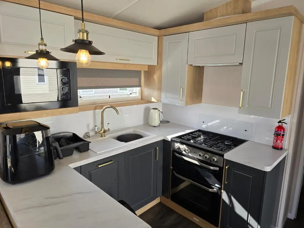a kitchen with white cabinets and a black stove top oven at 3 Bed-Sleeps 8-Free Parking-5 Min to Beach in Dornoch