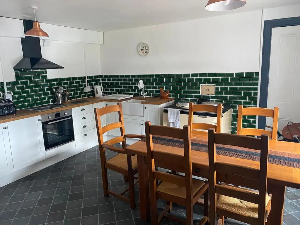 a kitchen with a table and chairs and green tiles at The old Farmhouse Minutes from lochness in Drumnadrochit