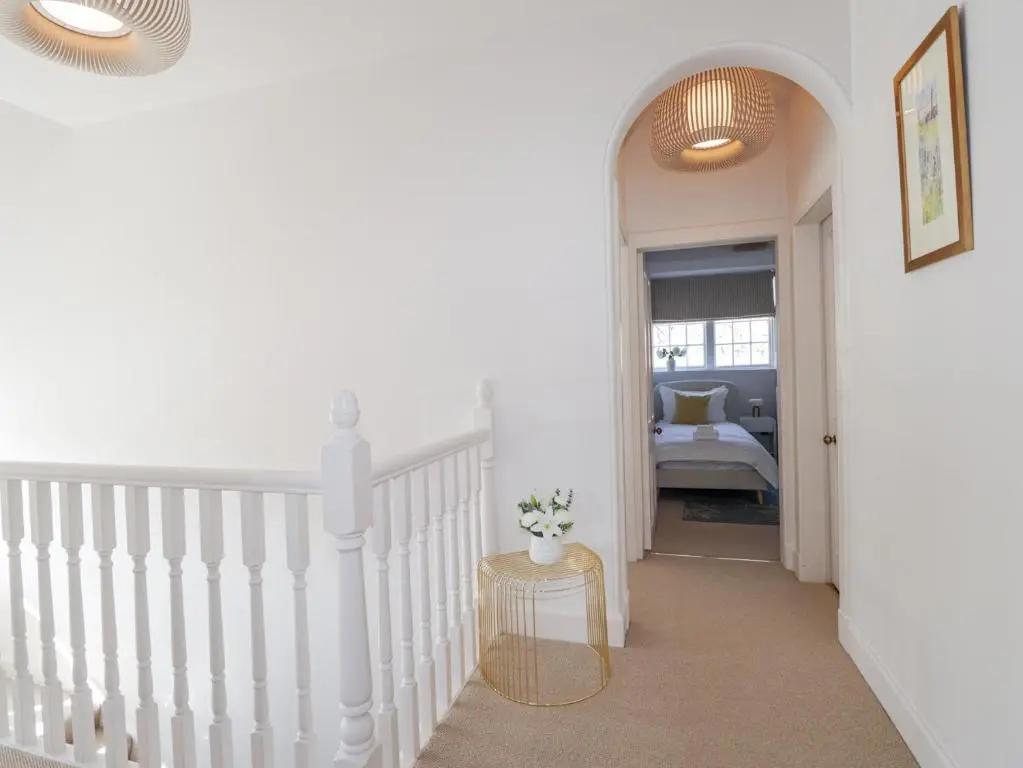 a hallway with a white staircase with a chair at Aspen Spa Apartment in Dornoch