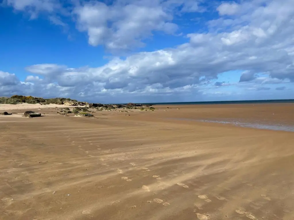 an empty beach with a blue sky and clouds at Aspen Spa Apartment in Dornoch
