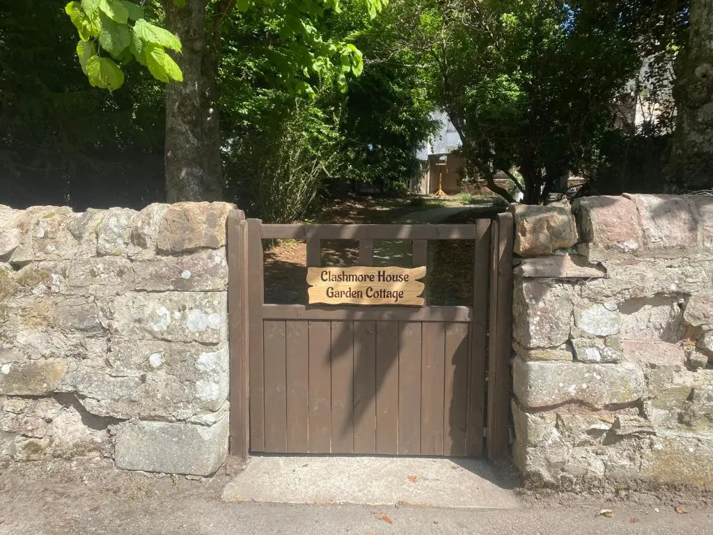 a gate in a stone wall with a sign on it at Clashmore House Garden Cottage Dornoch in Dornoch