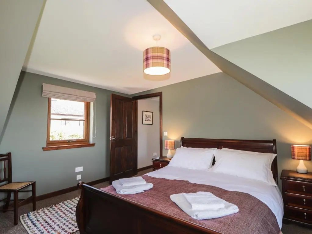 a bedroom with a bed with two towels on it at Fishers Cottage in Inverness