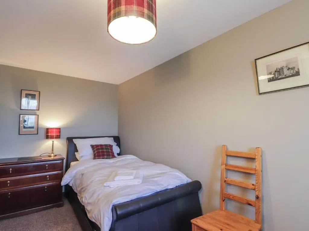 a bedroom with a bed and a wooden dresser at Fishers Cottage in Inverness