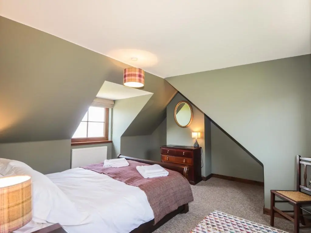 a attic bedroom with a bed and a mirror at Fishers Cottage in Inverness