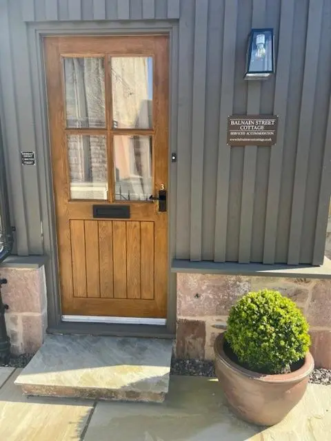 a door of a building with a plant in front of it at Balnain Street Cottage in Inverness