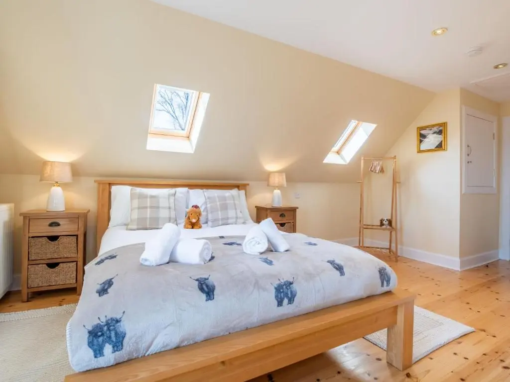 a bedroom with a large bed with a teddy bear on it at Villa Drover's Lodge by Interhome in Drumnadrochit