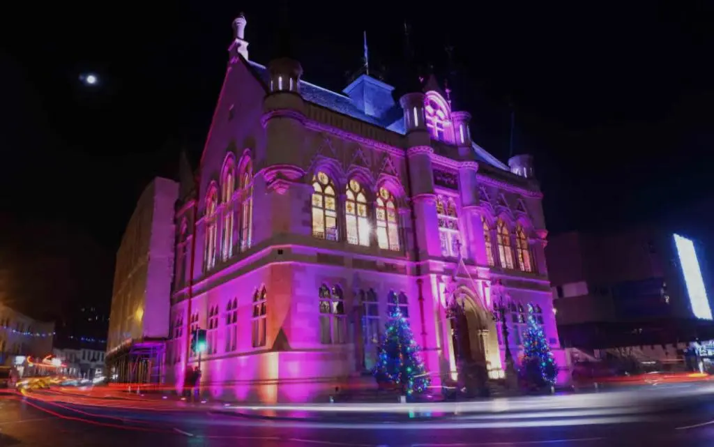 a building is lit up in purple at night at Inverness City Centre Apartment! in Inverness