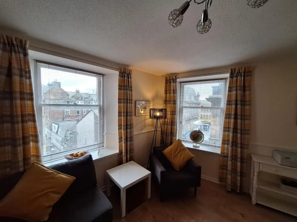 a living room with a couch and two windows at Inverness City Centre Apartment! in Inverness