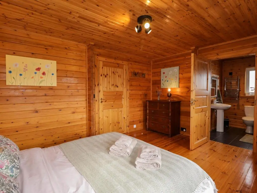 a bedroom with a bed in a wooden cabin at The Lodge in Beauly