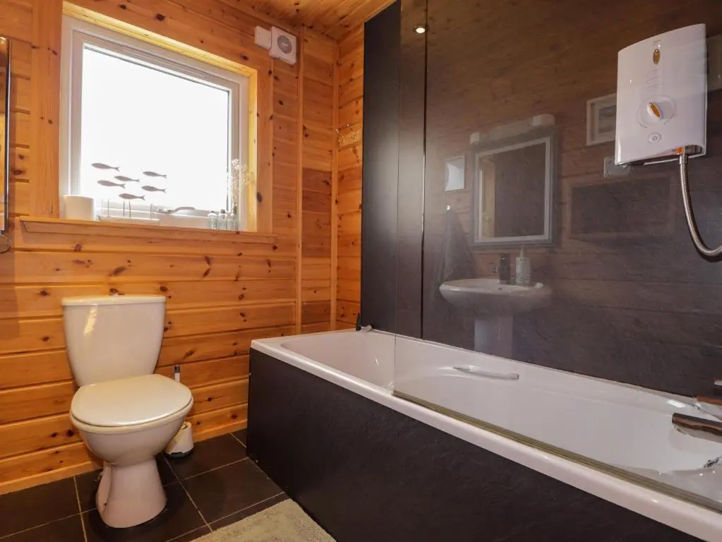 a bathroom with a toilet and a tub and a sink at The Lodge in Beauly