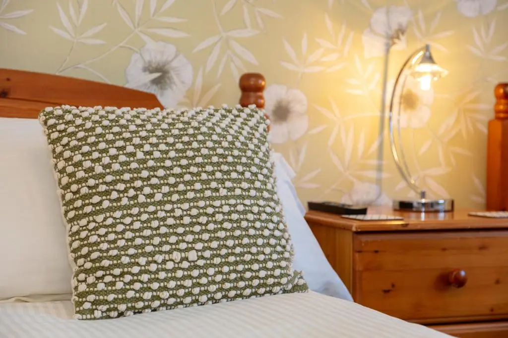 a pillow sitting on a bed next to a night stand at Old Surgery Guest House in Ullapool