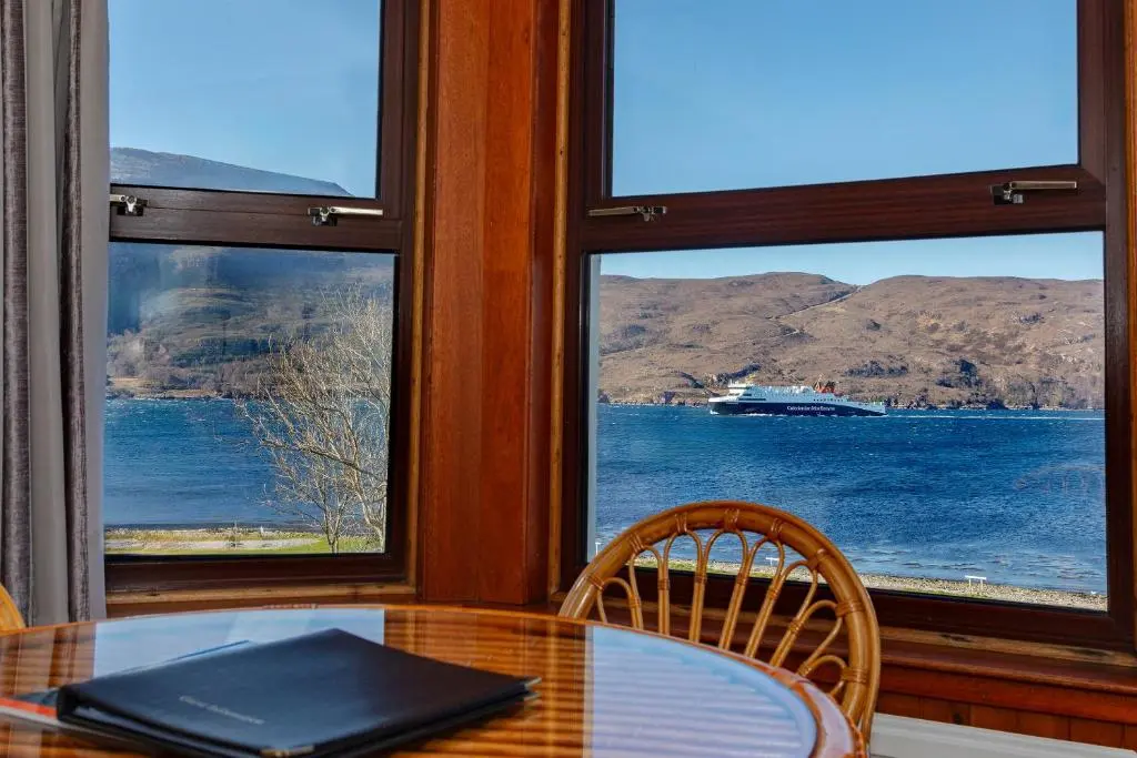 a dining room with a table and two windows at Old Surgery Guest House in Ullapool