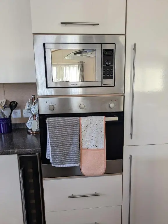a kitchen with a stove with a microwave at Dune Haven Luxury Beachside Lodge in Lossiemouth