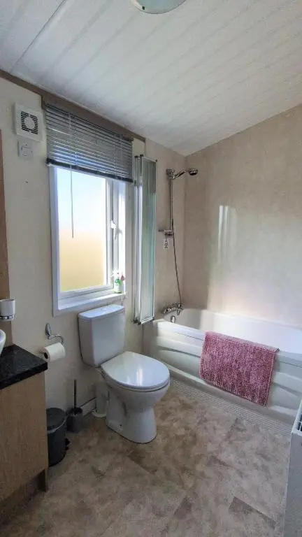 a bathroom with a toilet and a tub and a window at Dune Haven Luxury Beachside Lodge in Lossiemouth