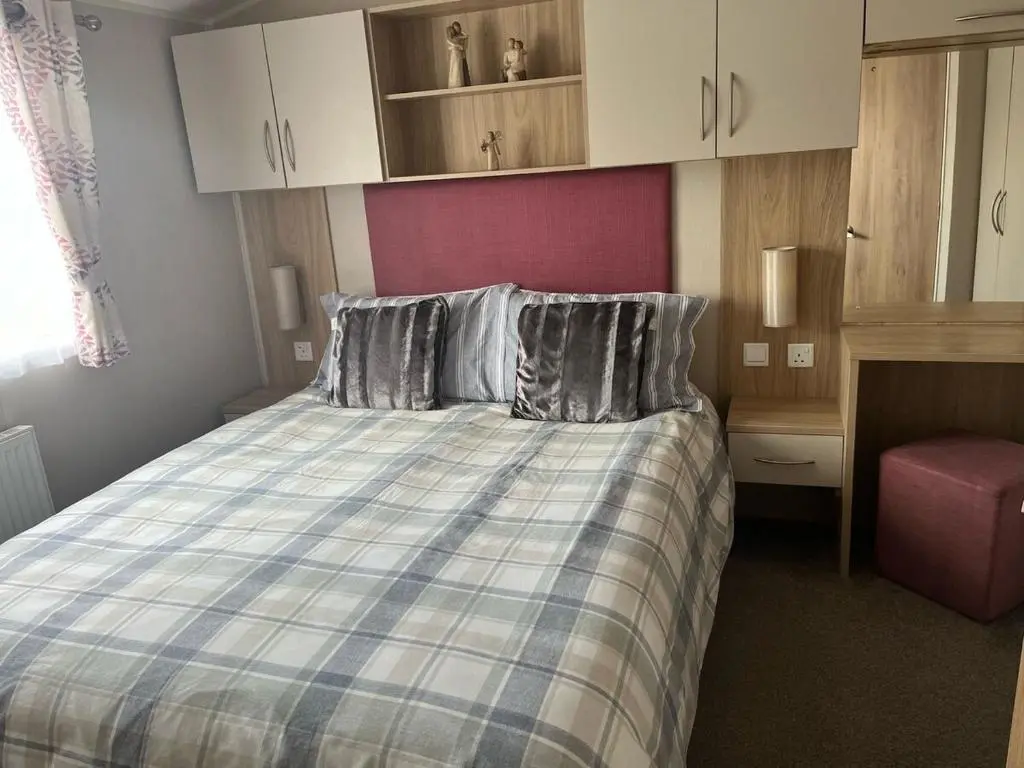 a bedroom with a bed with a blue and white blanket at Woodend Caravan in Shinness