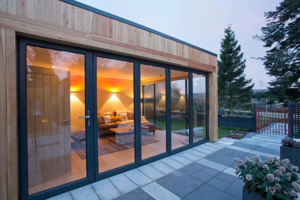 a glass extension of a house with a patio at The Invergarry - Royal Deeside Luxury 5 star Couples Retreat with Hot Tub, Aboyne in Aboyne