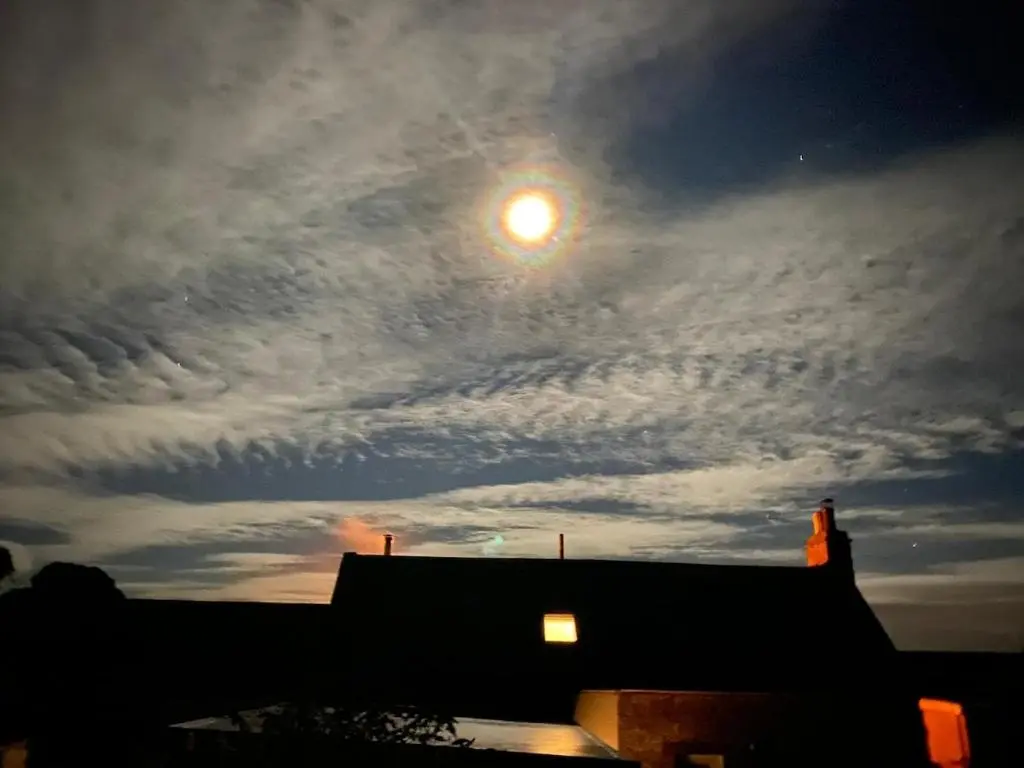 a cloudy sky with the moon behind a building at Cosy fisherman cottage in seaside village in Shandwick