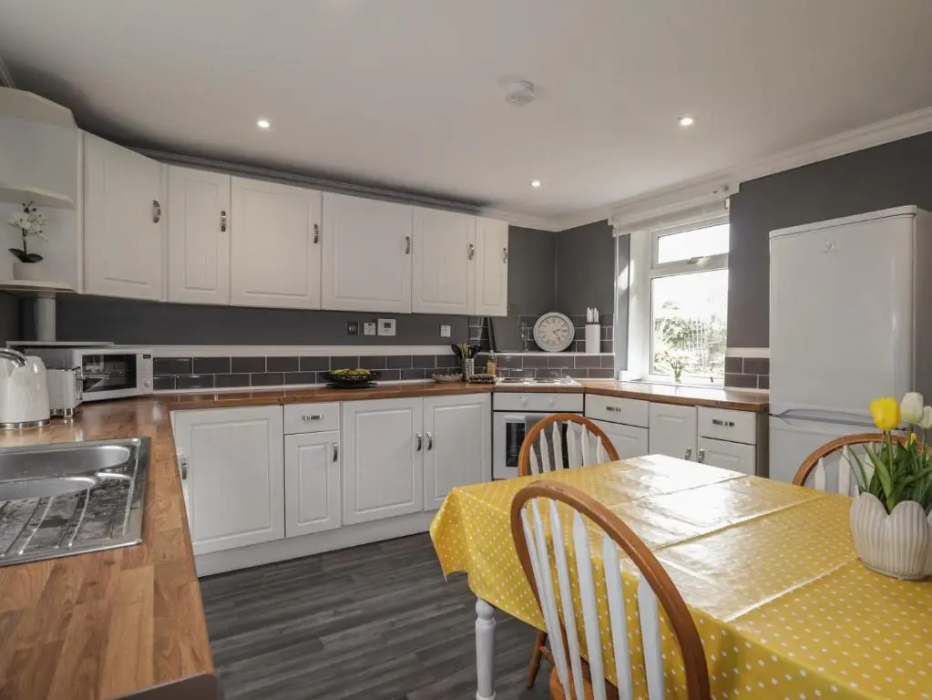 a kitchen with white cabinets and a table with a yellow table cloth at 6 New Street in Elgin