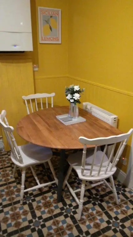 a wooden table with chairs and a vase of flowers on it at Cosy central 2 bedroom apartment - free parking in Inverness