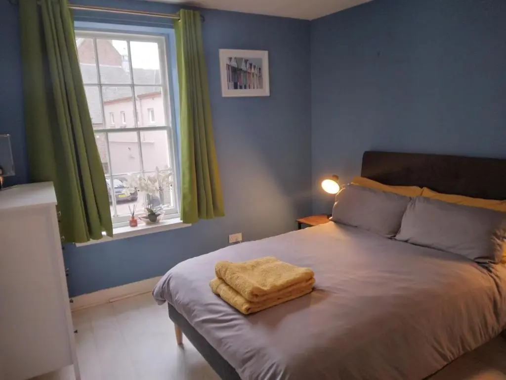 a bedroom with a bed with a towel on it at Cosy central 2 bedroom apartment - free parking in Inverness
