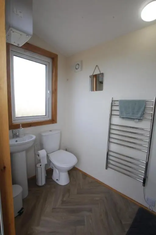 a bathroom with a toilet and a sink and a window at The Cairn Hut in Lybster