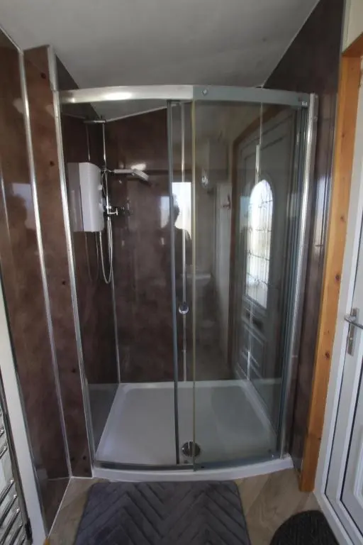 a shower with a glass door in a room at The Cairn Hut in Lybster