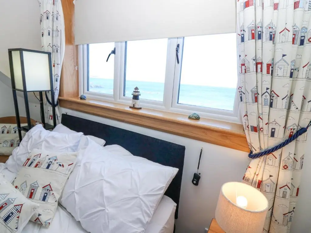 a bedroom with a bed and a window with the ocean at Periwinkle Cottage in Banff