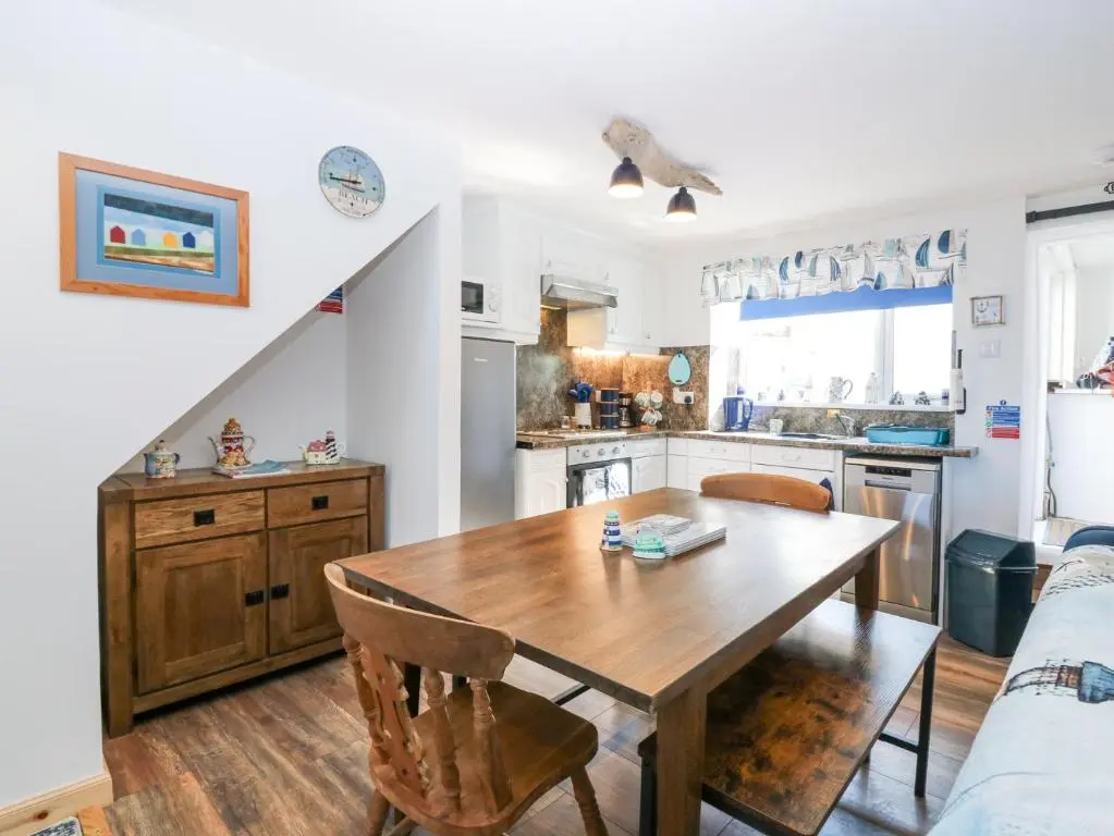 a kitchen and dining room with a wooden table at Periwinkle Cottage in Banff