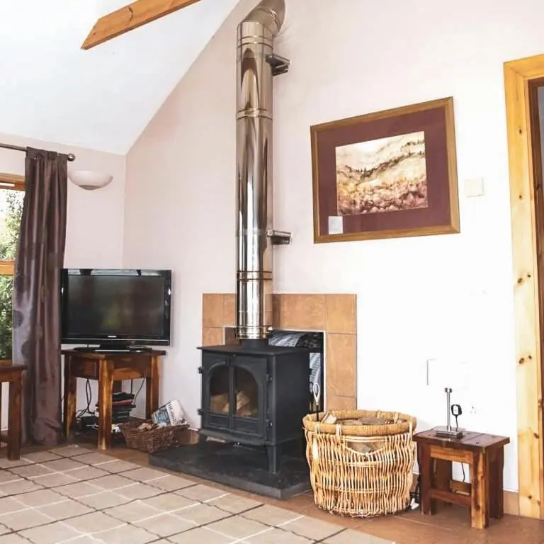 a living room with a fireplace and a tv at The Bothy in Lumphanan