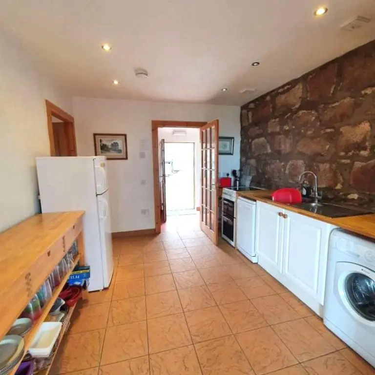 a kitchen with a white refrigerator and a stone wall at The Bothy in Lumphanan